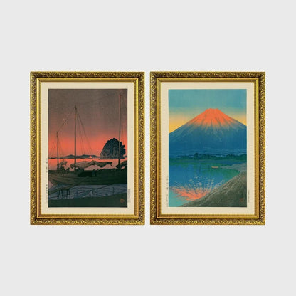 Set of 2 framed prints, Kawase Hasui Japanese woodblock prints: sailboats moored at a harbour at dusk; and Mount Fuji glowing red at sunset, reflected in the water — unframed