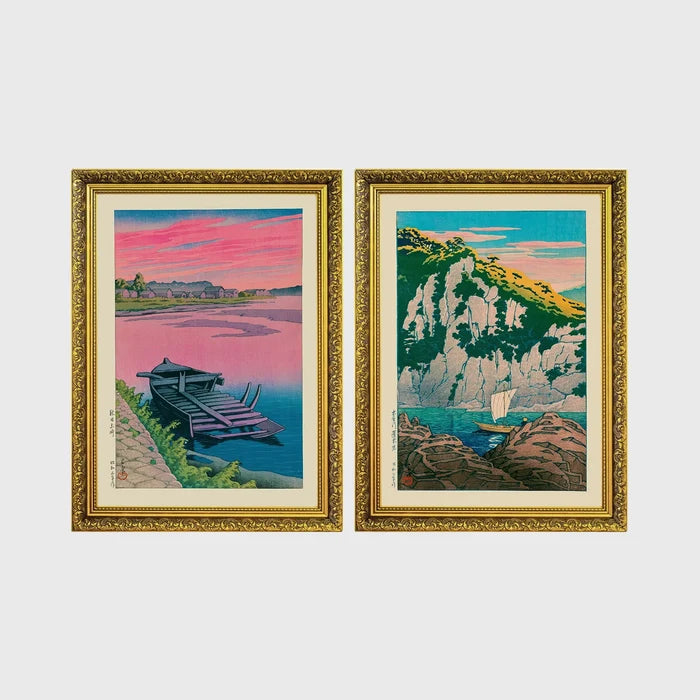 Set of 2 framed prints, Kawase Hasui Japanese woodblock prints: a pink sunset lake scene with a moored boat; and green coastal cliffs with a small sailboat — unframed