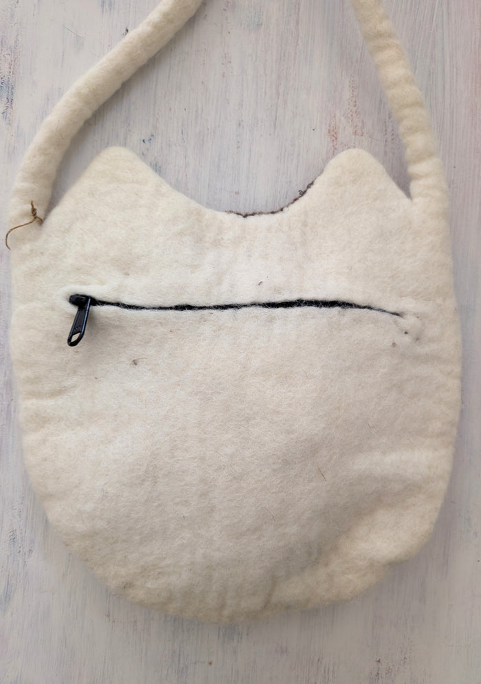 White textured bag with a black zipper on a light wooden surface