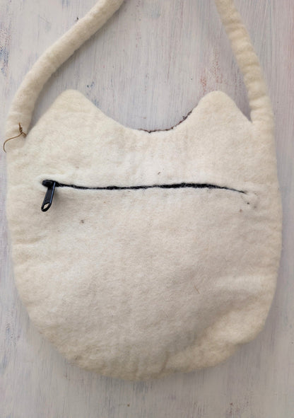 White textured bag with a black zipper on a light wooden surface