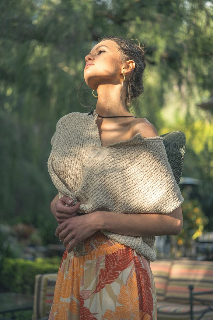 Woman wearing a beige shawl over her shoulders with a blurred outdoor background