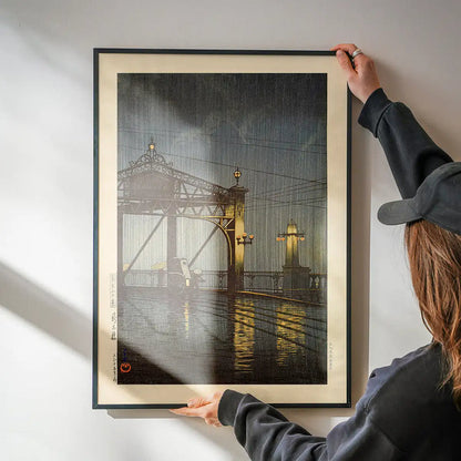 Shinohashi Bridge Print by Hasui Kawase being hung on a wall in a black frame